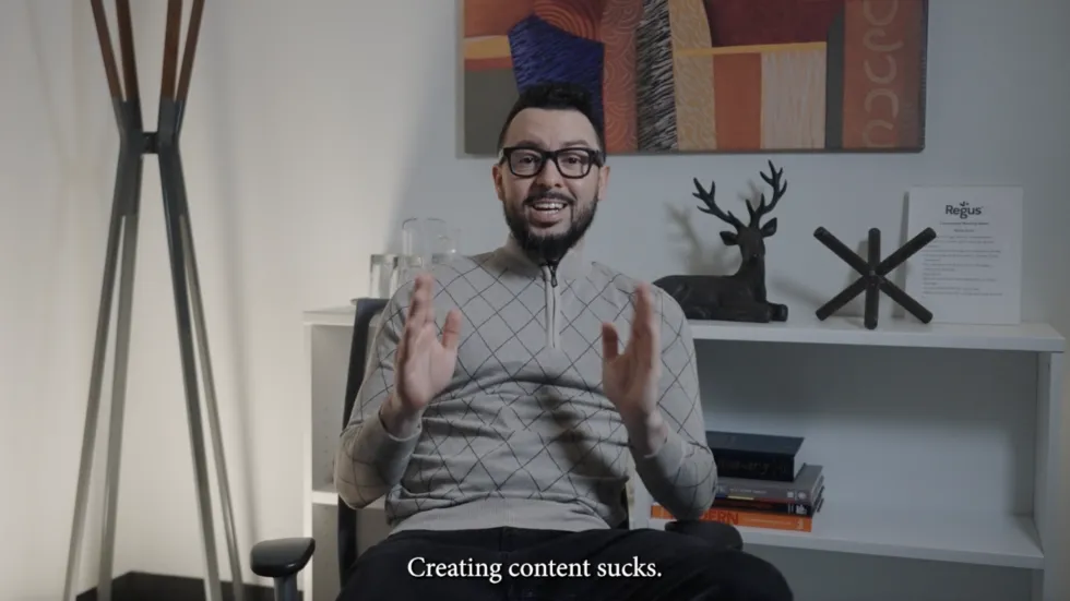 A person sits in a modern office setting, expressing frustration about content creation, with books and decor visible in the background